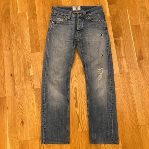 Tiger of Sweden jeans - Säljer ett par Tiger of Sweden jeans i storlek 30/30. Modellen heter chief, som har en rak och lite lösare passform. Jeansen är uppsydda några centimeter för att passa, då de tidigare hade längden ”34. De är i fint skick bortsett från något hål och slitningar på ena benet. De har även någon liten fläck som inte syns längst ned på fållen. Mått: Längd 100cm Midja 38cm Benöppning 19,5cm. Bara att höra av dig vid funderingar.✌️