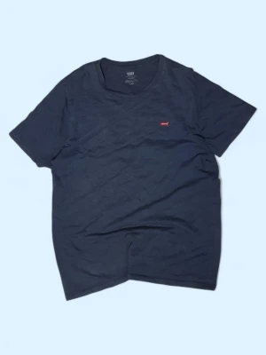 Mörkblå t-shirt från Levi's - Snygg mörkblå t-shirt från Levi's med klassisk rund hals och korta ärmar. T-shirten har en liten röd Levi's-logga på bröstet och är gjord i mjuk bomull som känns skön mot huden. Perfekt för en chill och stilren look.