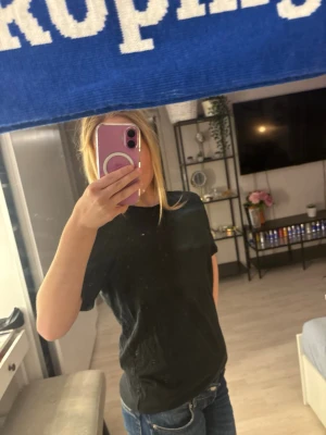 Svart t-shirt från Tommy Hilfiger - Säljer en svart t-shirt från Tommy Hilfiger i ekologisk bomull. Modellen är klassisk med korta ärmar och rund hals. Perfekt basic-plagg med snygg passform som funkar till jeans eller shorts. Märket syns på insidan av kragen.