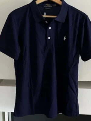 Marinblå Polo Ralph Lauren Piké  - Säljer denna stilrena, efterfrågade piké från Polo Ralph Lauren. Riktigt utmärkt kvalitet och väldigt snygg som passar allt. Skriv gärna vid intresse och för mer information! Tveka inte på att skicka bud. 