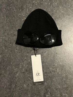 Svart C.P company mössa - Säljer en helt ny C.P company mössa. Den är helt oanvänd och är köpt på kids brand store för 1249kr. Hör av er om ni är intresserade.😃