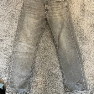 Grå relaxed jeans Chris 29/30 Jack and jones  - Säljer ett par grå jeans från Chris i relaxed fit, storlek 29/30. Byxorna har klassisk femficksdesign och raka ben med en snygg tvättad look. Perfekta för dig som gillar en chill och loose stil.