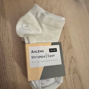 Vita strumpor 5-pack från Åhléns - Ett paket med 5 par vita strumpor från Åhléns. Perfekt för barn. Fem par klassiska vita strumpor från Åhléns i storlek 22-25. Tillverkade av ekologisk bomull med inslag av polyester och elastan för extra komfort och stretch. Perfekt för dig som gillar enkla och stilrena strumpor till vardags.