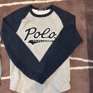 Grå och marinblå tröja Polo Ralph Lauren - Snygg grå tröja från Polo Ralph Lauren med marinblå ärmar och stor broderad logga framtill. 🙌