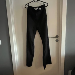 Svarta byxor från Pull&Bear - Svarta byxor från Pull&Bear i storlek M. Snyggt smal passform upptill med utsvängda ben nertill. Byxorna har hög midja och är tillverkade i ett mjukt bomullsmaterial med lite stretch för extra komfort. 