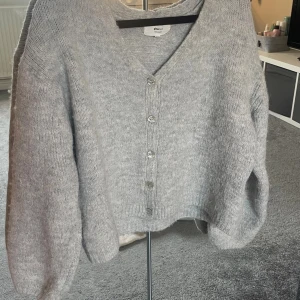 Grå kofta från Gina Tricot XS - Mysig grå kofta från Gina Tricot i ullblandning. Koftan har v-ringning, ribbade muddar och knappar framtill. Säljs då den inte kommer till användning så mycket❣️