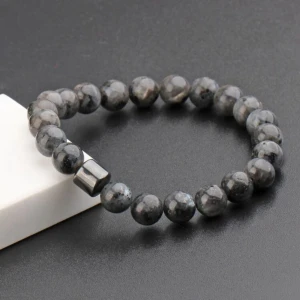 Grått pärlarmband - Stilrent armband med runda grå och svarta stenpärlor, ca 0,8 cm i diameter. Armbandet har en cool metallisk detalj som bryter av mot de mönstrade pärlorna. Perfekt för dig som gillar minimalistisk och modern stil.