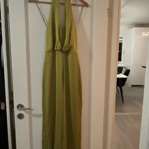 Byxdress från Zara  - Supersnygg byxdress  från Zara i en fräsch grön nyans. Byxdressen har halterneck, djup v-ringning och öppen rygg. Tillverkad i ett glansigt, mjukt material som ger en lyxig känsla. Perfekt för dig som vill sticka ut med stil och elegans.