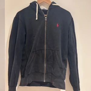 Svart hoodie från Polo Ralph Lauren - Svart hoodie från Polo Ralph Lauren med dragkedja. Den är ganska uttvättad men inga skador 