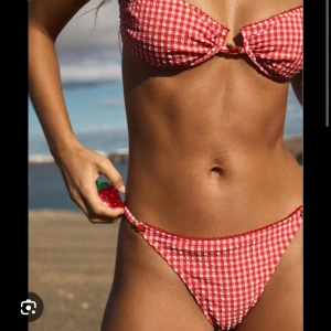 Rutig Bershka bikini  - Superfin bikini från bershka i rödvitt rutigt mönster. Toppen har bygel och en söt liten jordgubbsdetalj i mitten, och trosorna har smala band i sidorna. Perfekt för stranden och sommarens alla bad. Materialet är mjukt och stretchigt syntet.