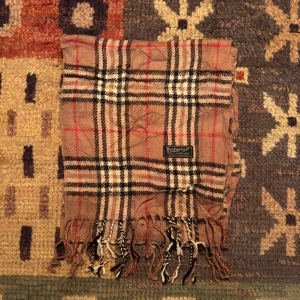 Vintage Burberry Halsduk  - -Riktigt bra skick. Nypris på dessa ligger på runt 5000kr, vilket gör detta till ett sjukt bra pris! Halsduken är gjord i Lamull, och är perfekt inför hösten och den kommande vintern. Anledningen till att det står ”Burberry’s” och inte ”Burberry” på lappen är eftersom halsduken är från några år tillbaka, innan de bytte namn! Om du har någon fråga är det bara att skriva till mig. /elgnce (5)
