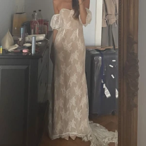 Romantisk offshoulder spetsklänning - Drömmig långklänning i champagnefärgad spets med offshoulder och puffiga ärmar. Klänningen har ett vackert blommigt mönster och en elegant släp. Perfekt för dig som vill sticka ut med en romantisk och feminin look. Från lulus!