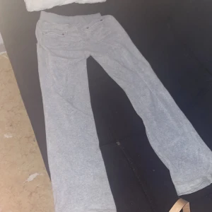 Grå mjukisbyxor Juicy Couture XS - Snygga grå mjukisbyxor från Juicy Couture i storlek XS. Byxorna har bred resår i midjan, två fickor med knappar framtill och ett avslappnat, rakt snitt. Perfekta för chill dagar och har en mjuk känsla i bomullsmaterial.