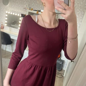 Vinröd klänning från Jeanette Biedermann - Supersöt vinröd klänning med 3/4-ärmar och rund halsringning från Jeanette Biedermann Collection. Modellen är kort med markerad midja och lätt utställd kjol. Mjuk och stretchig bomullskänsla, perfekt att ha på jul eller liknande 💯💋 Inget nopprig, använd 2/3 gånger. Kan sätta i skärp.