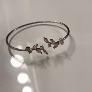 Silverfärgat armband med rosa stenar - Snyggt och tunt armband i silverfärg med dekorativa rosa stenar formade som blad och små klara kristaller. 🩷 aldrig använt 