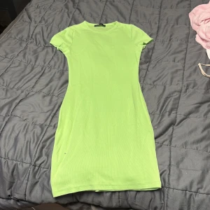 Ljusgrön ribbad klänning från New Yorker - Enkel och snygg ljusgrön ribbad kortklänning från New Yorker. Modellen är figurnära med korta ärmar och rund halsringning. Materialet är mjukt och stretchigt för extra komfort.