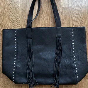 Svart väska med fransar - Köpt second hand och i mycket fint skick, men tyvärr lite för stor för min smak. Mått (cm): Bredd 35, Djup 12, Höjd 33.