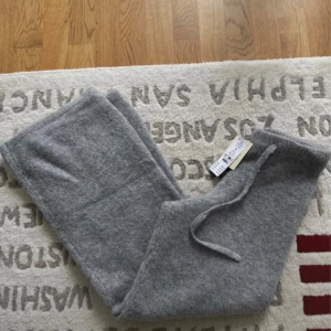 Grå stickade byxor med snörning S - Mysiga grå stickade byxor i melange med bred resår och snörning i midjan. Byxorna har en rak och avslappnad passform, perfekta för chill dagar. Materialet är mjukt och värmande, och modellen är loose och wide.