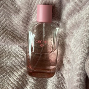 Zara Orchid  parfym - Snygg parfym från Zara med rosa detaljer och modern design. Perfekt för dig som vill ha en fräsch och trendig accessoar i din samling. Flaskan har en stilren look som passar in i alla miljöer.