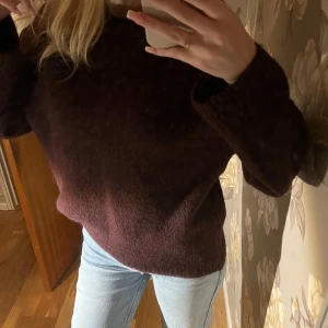 Mörk vinröd stickad tröja Gina Tricot - Mysig mörk vinröd stickad tröja från Gina Tricot i ullblandning. Tröjan har rund halsringning, ribbade muddar och en loose fit som ger en chill vibe. Perfekt att slänga på sig när det är kallt ute.