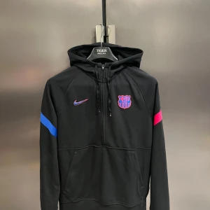 Svart barcelona hoodie från nike - Säljer en svart hoodie från barcelona som jag köpte på stadium för nått år sen! Hoodien har dragkedja och färgdetaljer i blått och rosa på ärmarna. Den är i riktigt bra skick utan några defekter!