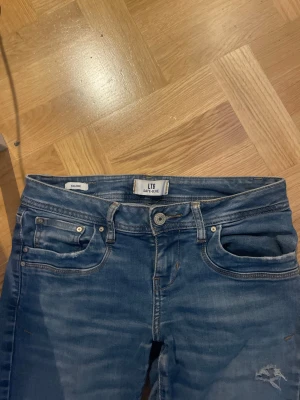 Blå lågmidjade bootcut jeans från LTB Valere W27 L32 - Snygga blå jeans från LTB, modell Valere, med snygga hål på benen och coola detaljer både fram- och bakfickor. Jeansen har normal och snygg passform och är tillverkade i jeanstyg med snygga kontrastsömmar. Perfekt för dig som gillar en avslappnad stil❤️❤️❤️