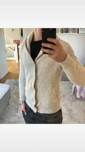 Beige stickad kofta med sjalkrage - Säljer en beige stickad kofta från mango med sjalkrage och snygga knappar framtill. Koftan har två fickor på sidorna och är långärmad med ribbade muddar. Perfekt för dig som gillar en chill och stilren look under höst och vinter. Strl S