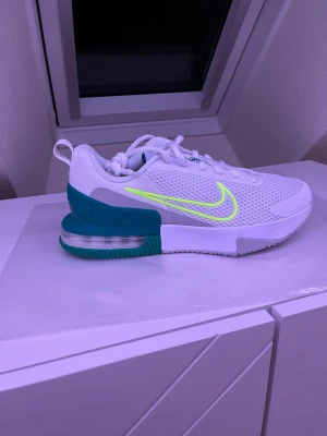 Nike Air Max  - Nike Air Max alpha 6 träningsskor i vitt mesh med turkosa detaljer och en neongul swoosh på sidan. Skon har en tydlig Air Max-sula med synlig luftbubbla och snörning framtill. Perfekt för dig som gillar sportig och fräsch stil. Det är bara en sko eftersom jag måste köpa 2 olika par och har då denna till ett billigt pris