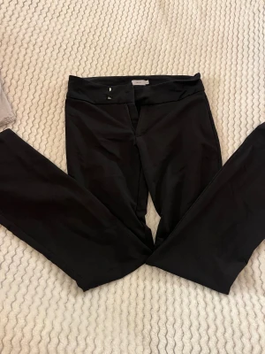 Svarta kostymbyxor från Nelly  - Snygga svarta low waist bootcut kostymbyxor från Nelly i storlek XS. Fästet där man knäpper byxorna har börjat gå av, men går fortfarande att stänga. 