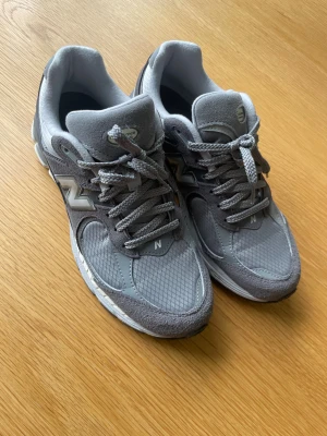 New Balance 2002R grå sneakers - Grå New Balance 2002R sneakers med mesh och mocka-paneler, klassisk N-logga på sidorna och robust sula med ENCAP och N-ergy-dämpning. Skorna har snörning och en sportig, chunky siluett som är riktigt trendig just nu.