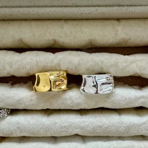 Bred ring i guld och silver - Coola breda ringar med organisk, vågig yta i både guld- och silverfärg. Perfekt statement piece med modern känsla och blank finish. Säljs separat eller som par, passar dig som gillar att sticka ut med accessoarer.