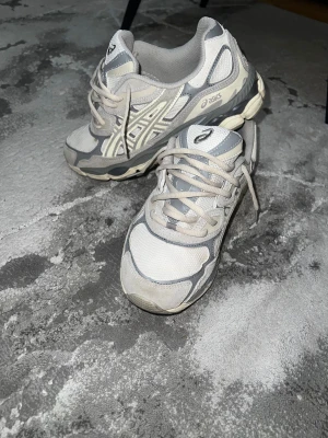 Grå och vita Asics sneakers 41.5-40 - Säljer ett par Asics sneakers i storlek 41.5 med snyggt grått och vitt mesh- och syntetmaterial. jag har haft på mig dom typ 2 gånger dom blev för små så jag tänker sälja dem. de passar 40-41.5