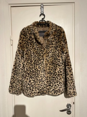 Leopardmönstrad pälsjacka Claude Gérard - Säljer en fluffig och snygg pälsjacka från Claude Gérard i leopardmönster. Jackan är beige med svarta och bruna detaljer, har stora knappar framtill och ett lent, champagnefärgat foder. Perfekt för dig som vill sticka ut med en cool look.