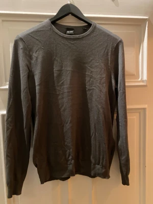 Grå långärmad tröja only sons - En enkel och stilren grå långärmad tröja från only sons. Tröjan har rund hals och är tillverkad i ett mjukt material som känns skönt mot huden. Perfekt att matcha med jeans eller chinos för en clean look.