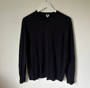 Mörkblå stickad tröja i ull, S - Mörkblå stickad tröja från Arket i storlek S, tillverkad i 100% ull. Tröjan har rund hals och långa ärmar med ribbade muddar vid hals, ärmslut och nederkant. Enkel och stilren design som funkar till många olika looks.