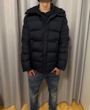 Mörkblå dunjacka från J.Lindeberg - Snygg mörkblå dunjacka från J.Lindeberg med huva och diskret logga på ärmen. Nyskick använd 2 gånger inga deffekter, storlek L men passar som M också. Nypris-5000kr mitt pris-3000kr