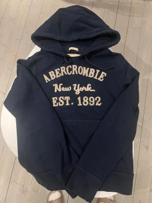 Abercrombie & Fitch mörkblå hoodie  - Abercrombie & fitch mörkblå hoodie vintage väldigt sällsynt och unik säljs inte längre. I bra skick 8/10 inget som märks. Storlek Medium pris 638 kr skriv vid frågor 😃