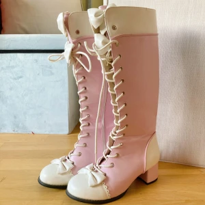 Rosa och vita knähöga lolita boots  - Jättefina knähöga stövlar från Bodyline. Snörning framtill och dragkedja på sidan. Skorna har chunky låg klack, rund tå och stora vita rosetter både upptill och på tån. 💖Perfekta för en sweet lolita vinter coord ❄️💖Japansk storlek 25, uppskattas till EU 39 🎀