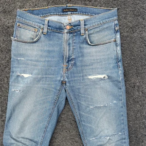 Nudie Jeans Lean Dean - Säljer ett par blåa slim jeans från Nudie med slitningar. Om det är någon slitning man inte gillar går det att ta bort helt gratis i en nudie butik. Jeansen är riktigt sköna - tillverkade i fin bomull. Perfekt för en stilig look. W32 L34. Tveka inte på att höra av dig vid minsta tanke eller fundering! 😁