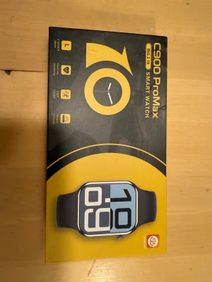 C900 ProMax svart smartklocka - Säljer en C900 ProMax smartklocka med stor 2,19-tums skärm och svart silikonarmband. Klockan har fyrkantig form, aluminiumhölje och kommer med laddare och extra armband. Funktioner som pulsmätning, stegräknare, musikstyrning och väder finns. Perfekt för dig som gillar teknik och vill ha koll på hälsan.