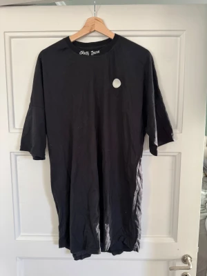 Svart oversized t-shirt Sixth June - Svart oversized t-shirt från Sixth June med tryck på bröstet och ryggen. Rund hals med broderad logga och coolt emblem framtill. Materialet är mjuk bomull och modellen har lite längre korta ärmar för en avslappnad streetwear-look.