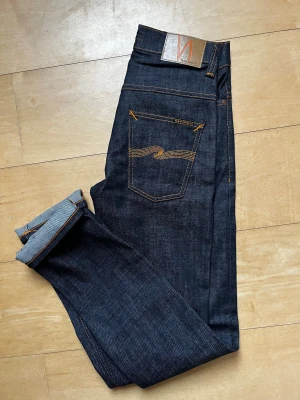 Mörkblå jeans från Nudie Jeans - Hej, jag säljer dessa riktigt coola Nudie-jeans, de är helt nya, de är i 10/10 skick. Modellen är Thinn finn. Storleken är W28 L32. Jag säljer dem eftersom de är lite små för mig. Skriv gärna om du har några frågor.