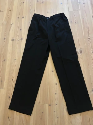 Svarta kostymbyxor från Only & Sons - Stilrena svarta kostymbyxor från Only & Sons med loose fit. Klassisk rak modell med knapp och dragkedja i midjan. Perfekta för dig som gillar en avslappnad men ändå dressad look.