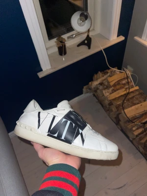 Valentino Garavani VLTN sneakers - Säljer ett par feta Valentino Garavani VLTN sneakers i vitt skinn med svart band över snörningen och stor vit stjärna. Du får med box och påsar och nya skosnören vid köp✅
