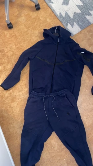 Nike tech tracksuit - Säljer ett par mörkblå mjukisbyxor från Puma med bekväm passform och snörning i midjan. Byxorna har elastisk midja och är perfekta för chill eller träning. Snyggt sportigt utseende med diskret Puma-logga på benet.
