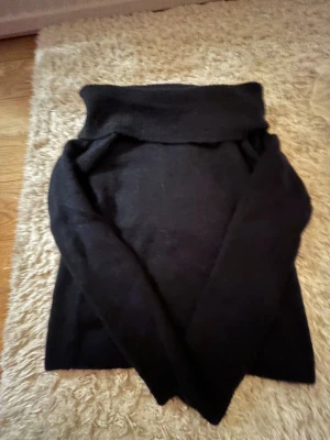 Svart polotröja i stickat material - Mysig svart polotröja i stickat material med lång ärm och hög krage. Perfekt för kyliga dagar och enkel att matcha med jeans eller kjol. Klassisk och stilren design som funkar till det mesta.