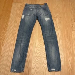 Acne  jeans 28/32 - Säljer ett par blå vintage Acne  jeans i klassisk straight modell. Asnice slitningar och detaljer. W28 L32 passar också W29