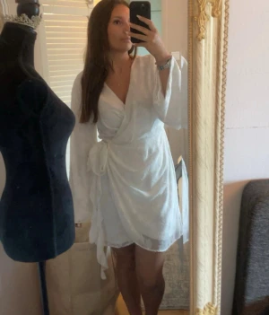 Vit blommig klänning med knyte  - Säljer en av mina favorit klänningar från förra sommaren då den är för stor för mig! Jätteskönt material och luftig till sommar eller utomlands!