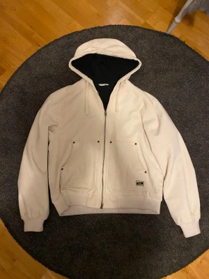 Beige manchesterjacka med huva från Zara - Säljer en beige manchesterjacka från Zara med huva och dragkedja. Knappt använd och nypris runt 700kr Jackan har två stora fickor framtill, ribbade muddar och quiltat svart innerfoder. Snygg detalj med patch från Jalur på ena fickan. Perfekt för dig som gillar streetwear-vibe.