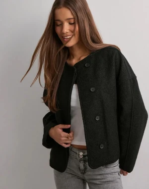 Svart kappa med knappar - Säljer en svart kappa med oversized passform och stora knappar framtill. Jackan har rund halsringning och långa ärmar. Perfekt för dig som gillar en chill och trendig look. Ny utan prislapp i storlek XXS😊